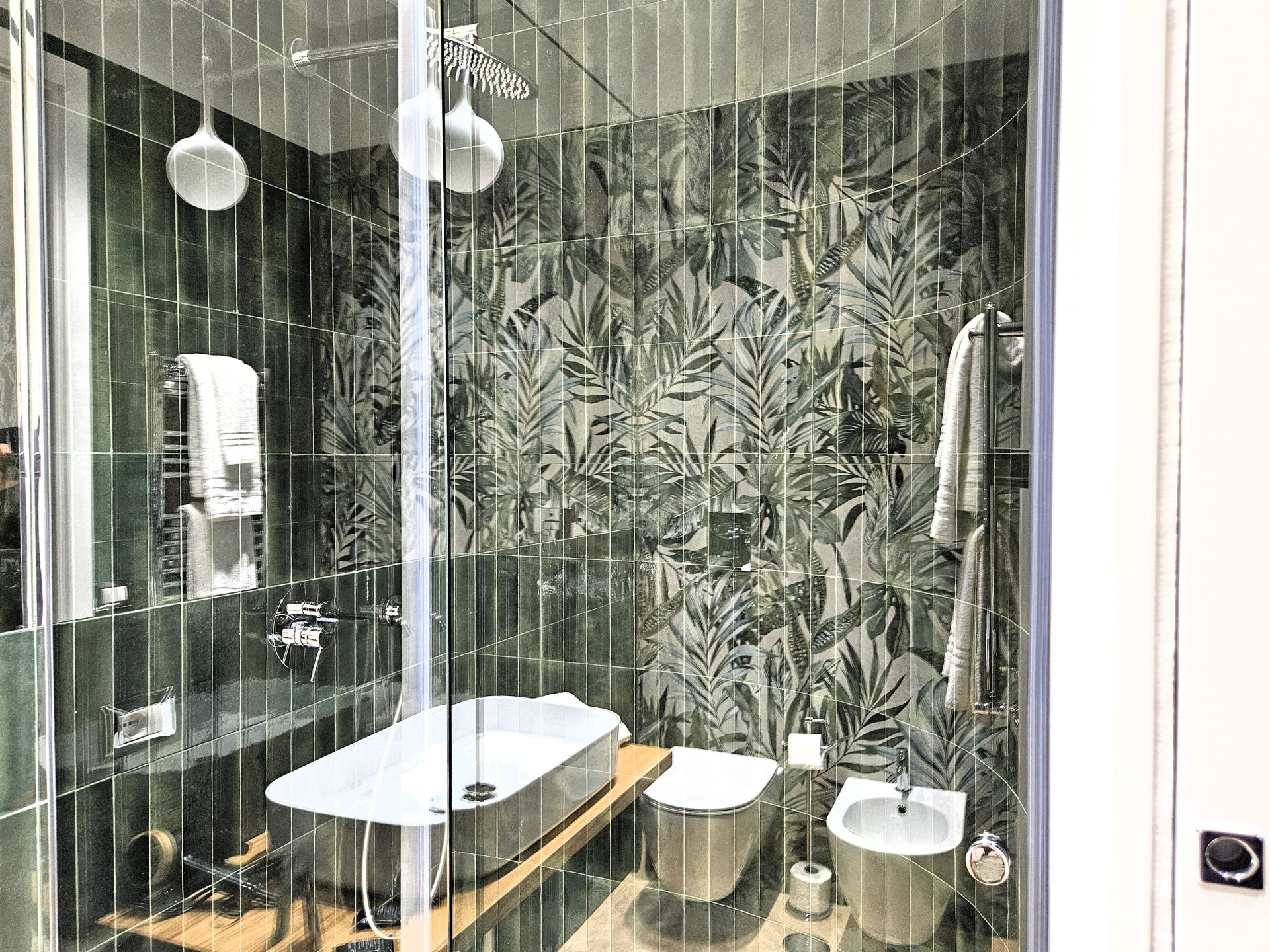 Bagno con doccia in cristallo e rivestimento a foglie